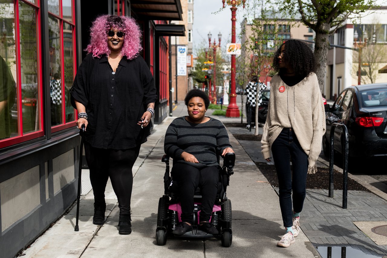 Three friends walking and rolling down a city sidewalk