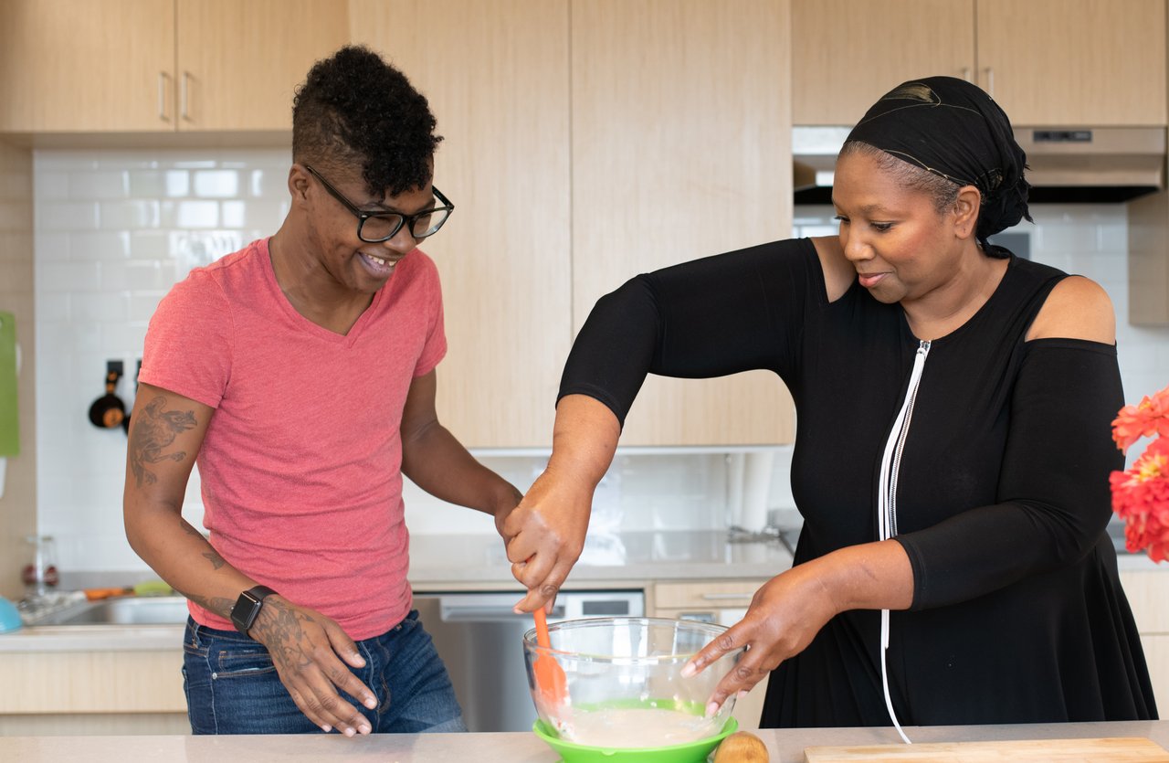 Two disabled people mix batter and bake together in a kitchen