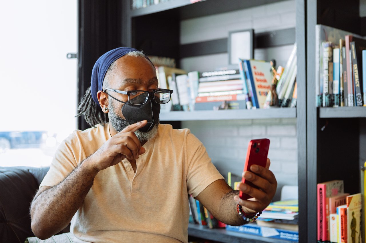 A Deaf man signs with one hand during a video call on his phone