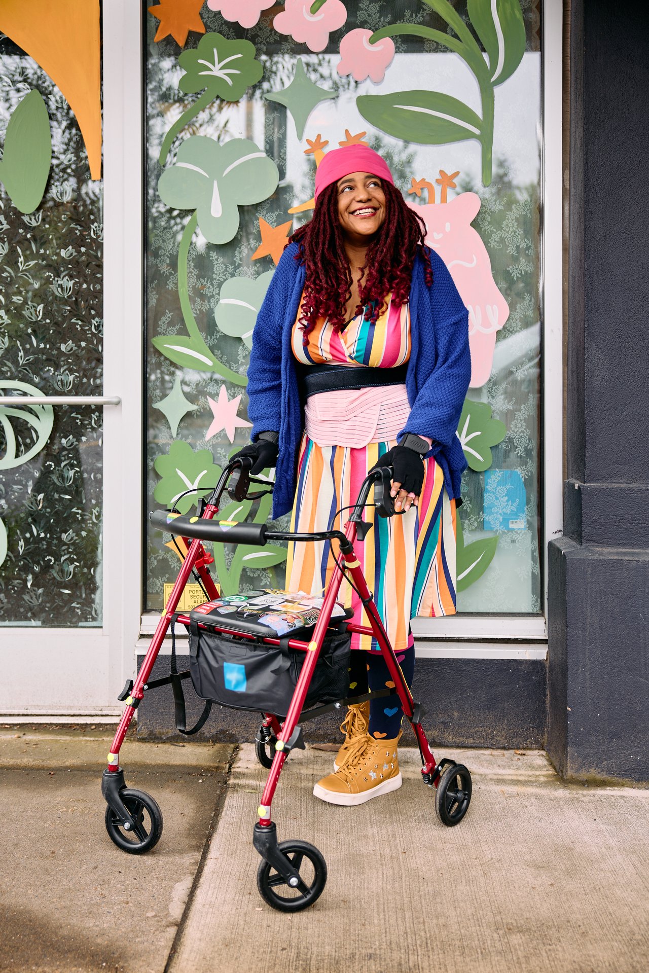 A person with a sticker-covered rollator smiles outside a shop