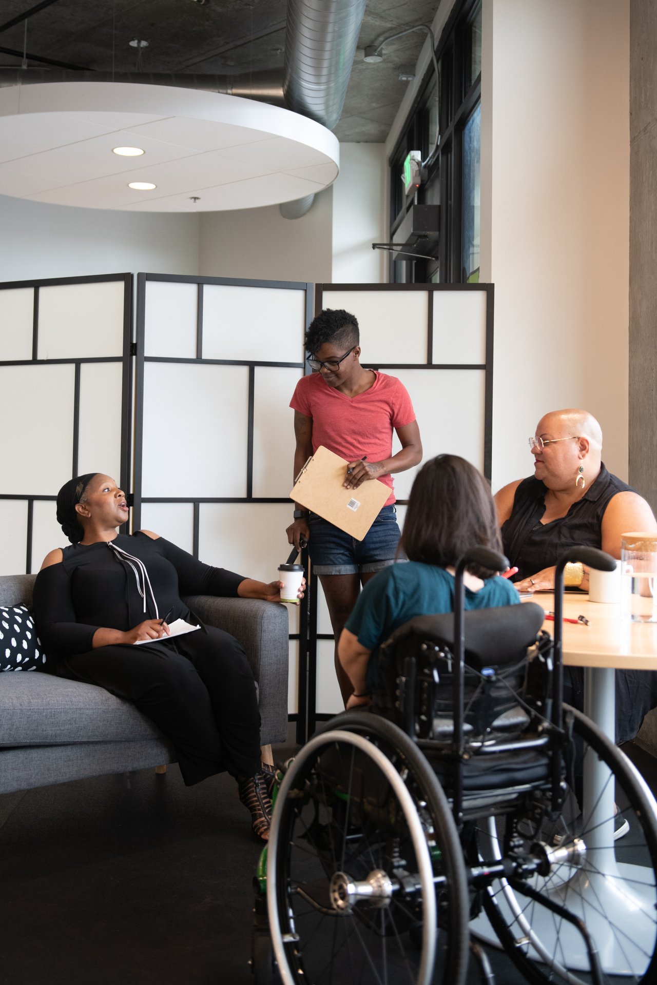 A disabled woman speaks while three others listen around a table during a meeting