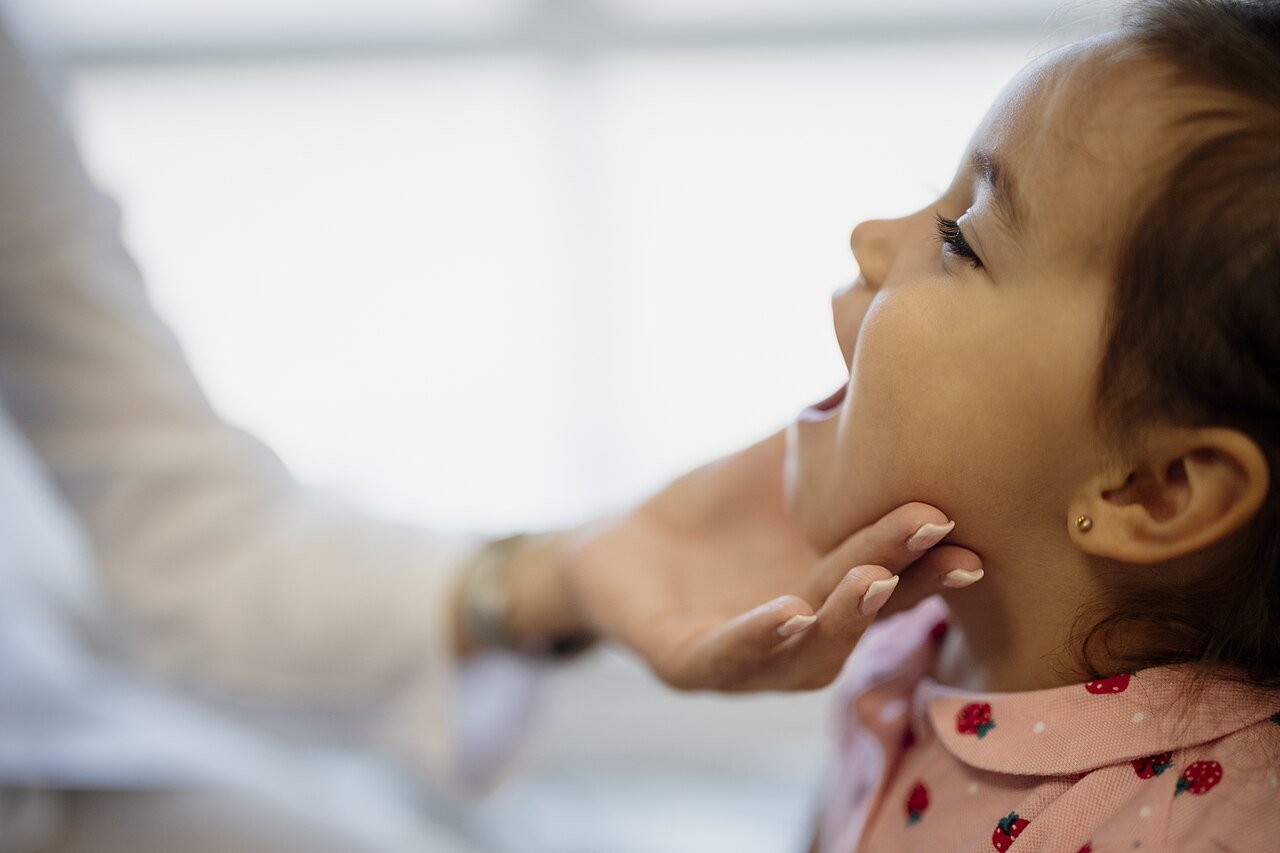 A dentist gently holds a young child's chin during a dental checkup
